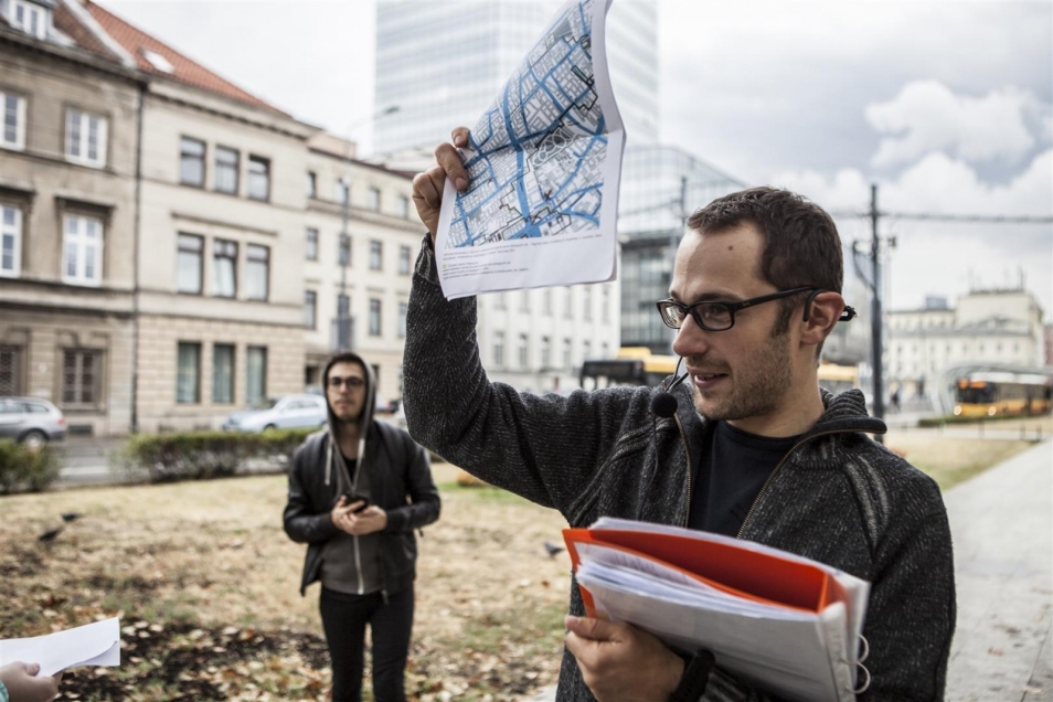 Spacer po Warszawie. Mężczyzna, najprawdopodobniej przewodnik, trzyma w górze mapę.