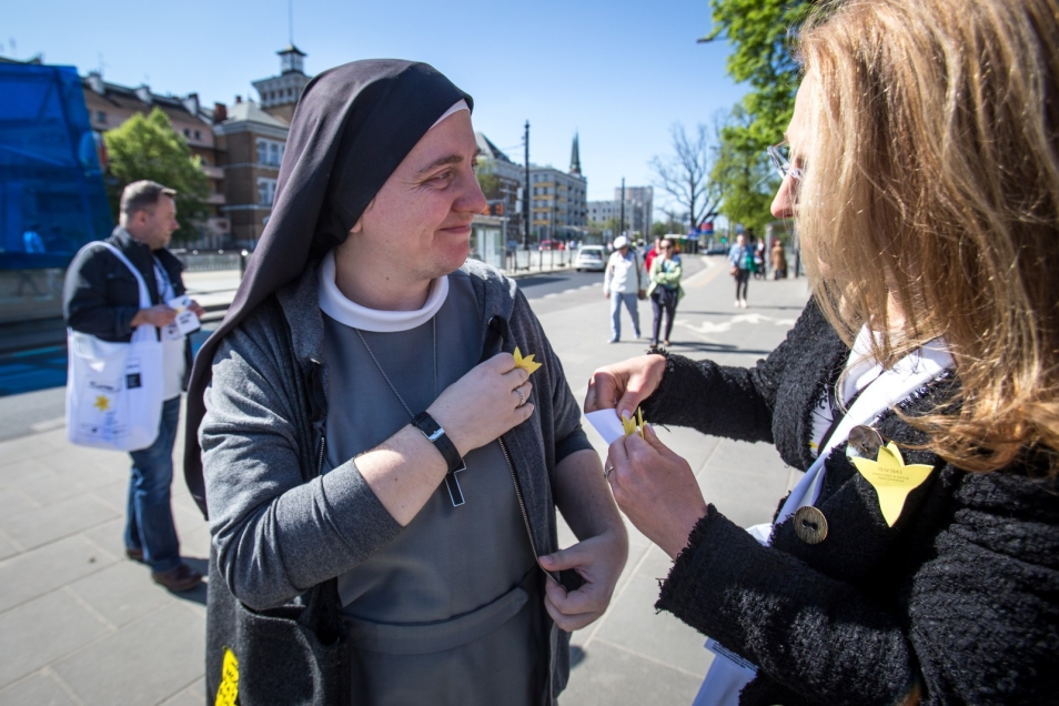 Wolontariusze akcji społeczno-edukacyjnej Żonkile 2018 przypinają przechodniom papierowe żonkile.