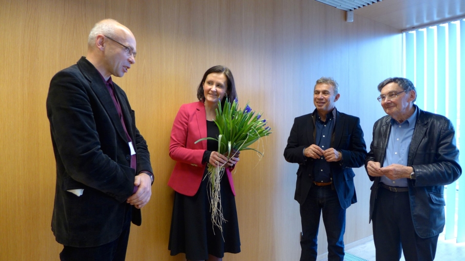 Dariusz Stola, Piotr Wiślicki i Marian Turski, pomiędzy nimi stoi kobieta z kwiatami.
