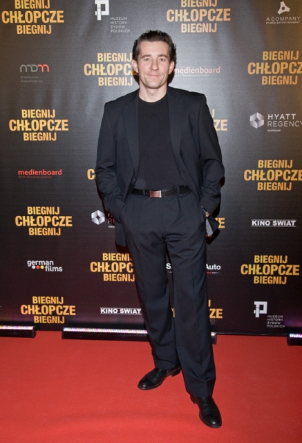 Przemysław Sadowski pozuje przy ściance z tytułem filmu "Biegnij, chłopcze, biegnij".
