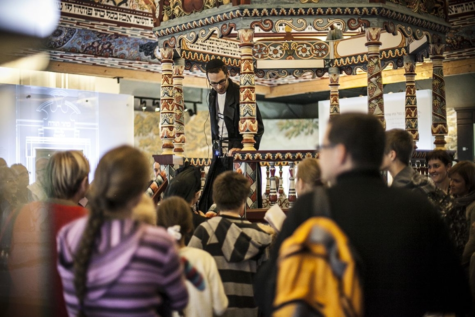 Grupa zwiedzających stoi przy rekonstrukcji synagogi w Muzeum POLIN.