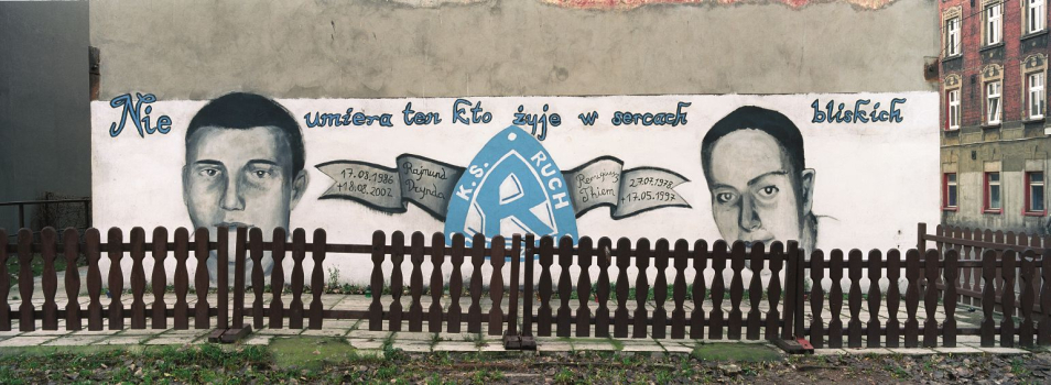 Za płotkiem zajmuje się mural z napisem Nie umiera ten, kto żyje w sercach bliskich.