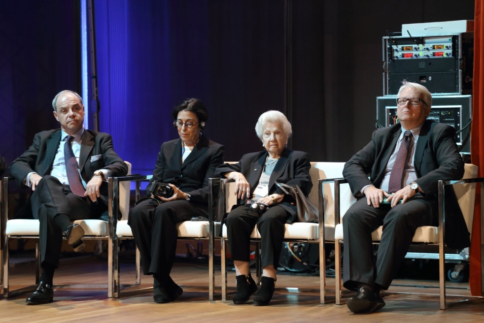 Kilka osób siedzi na krzesłach podczas konferencji.