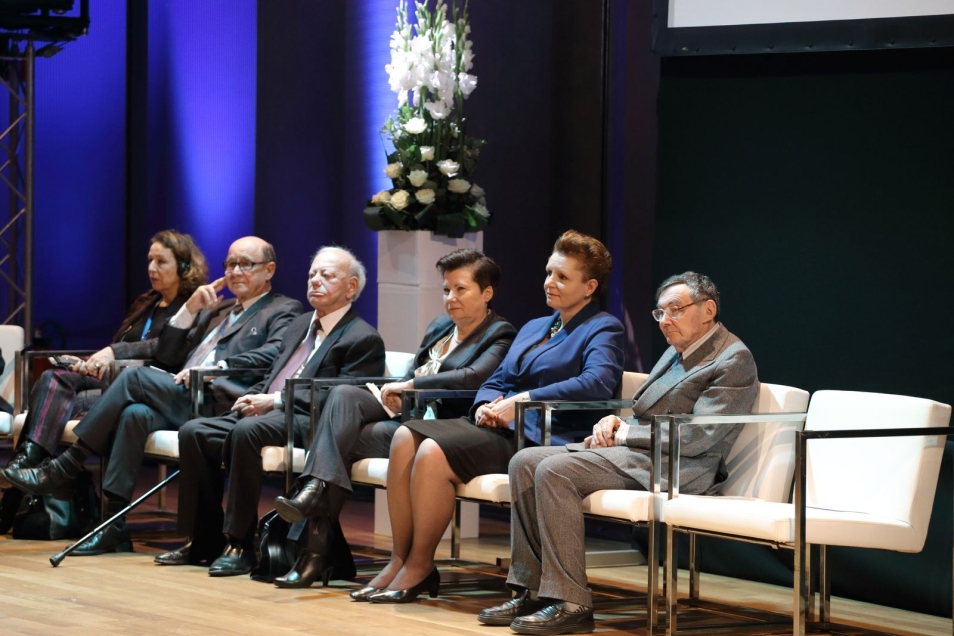 Kilka osób siedzi na krzesłach podczas konferencji.
