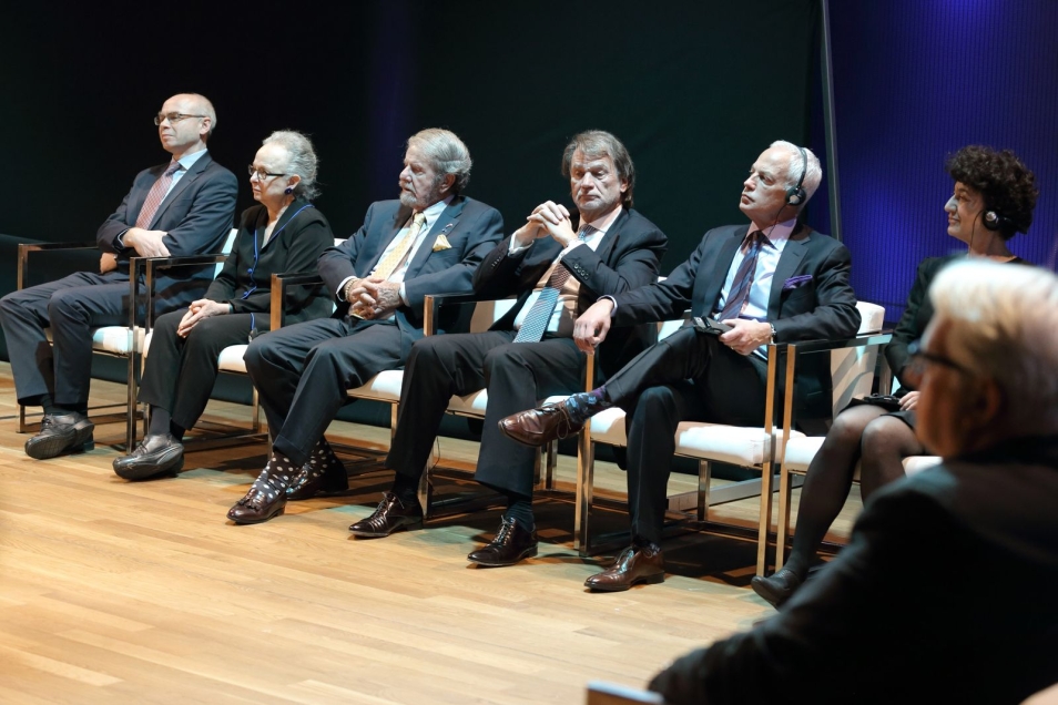 Kilka osób siedzi na krzesłach podczas konferencji.