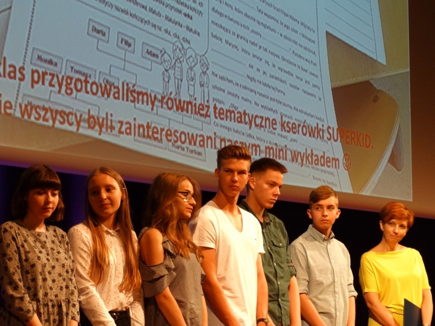Grupa młodzieży stoi na scenie.