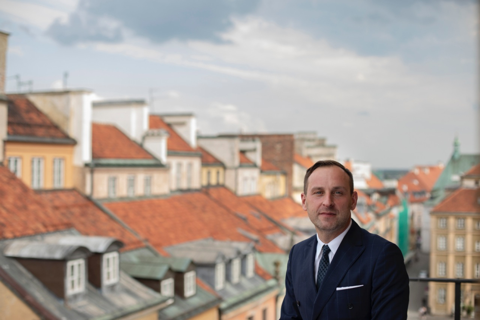Dr Jarosław Trybuś, w tle widoczne dachy warszawskiego Starego Miasta, fot. Dawid Żuchowicz