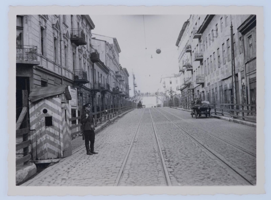 Mężczyzna w nazistowskim mundurze stoi przy budce strażniczej w łódzkim getcie.