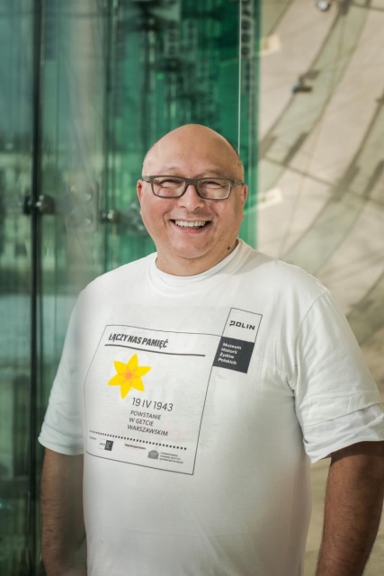 Wolontariusz akcji Żonkile przy szklanej ścianie Muzeum Polin