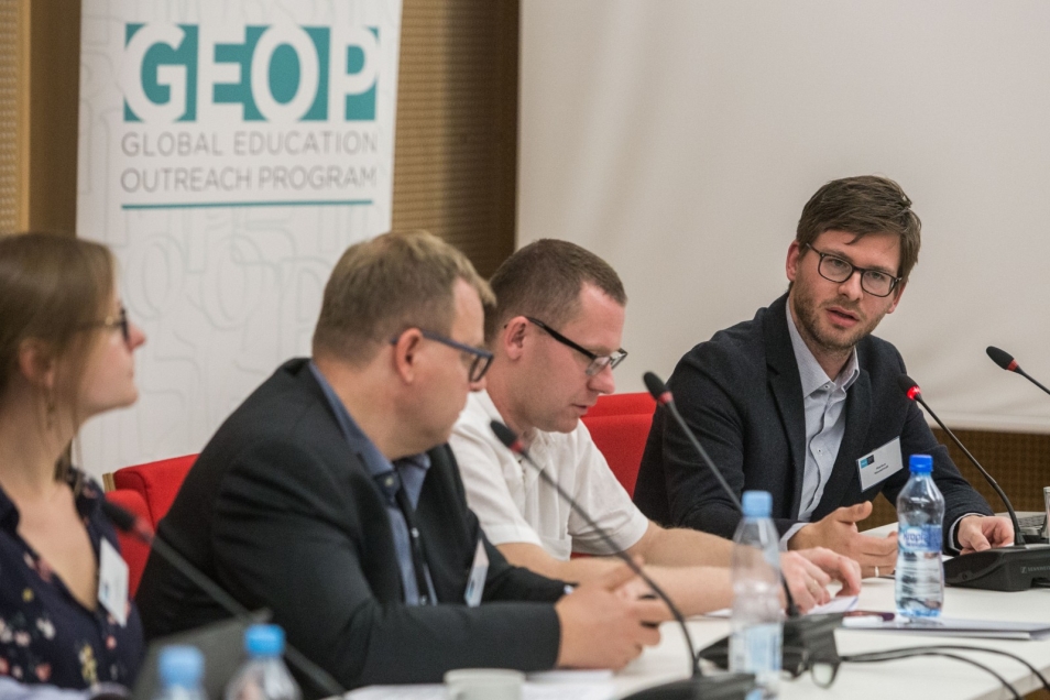 A woman and three men are attending the Global Education Outreach Programme conference.