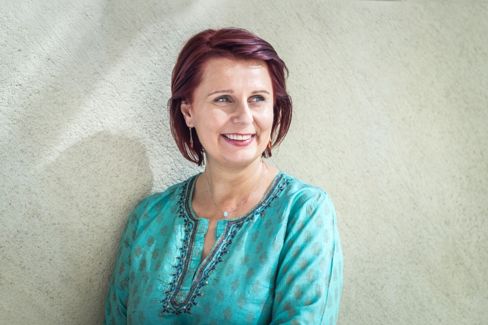 Uśmiechnięta brunetka w turkusowej bluzce.