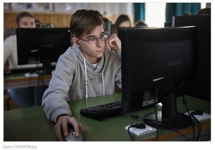 Zajęcia na platformie IWitness, Na zdjęciu: Chłopiec siedzi w ławce przed monitorem komputera