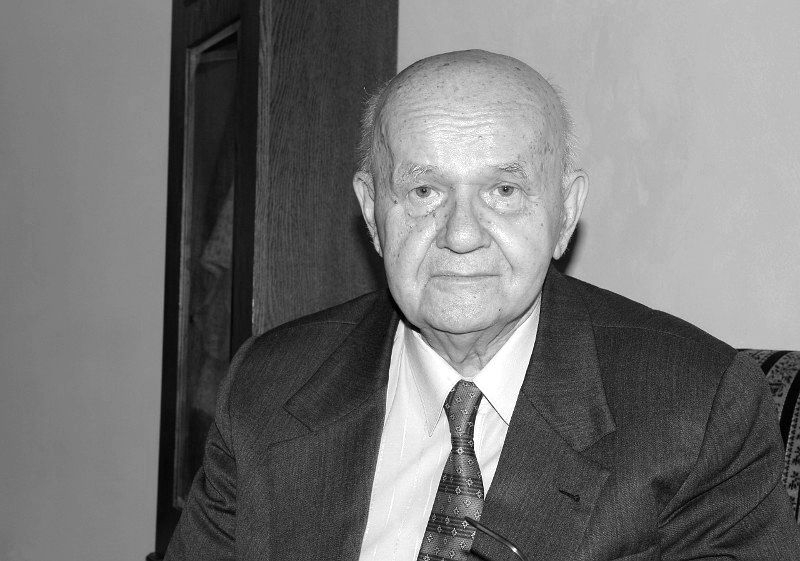 Janusz Tazbir. Zdjęcie przedstawia łysego mężczyznę w garniturze.