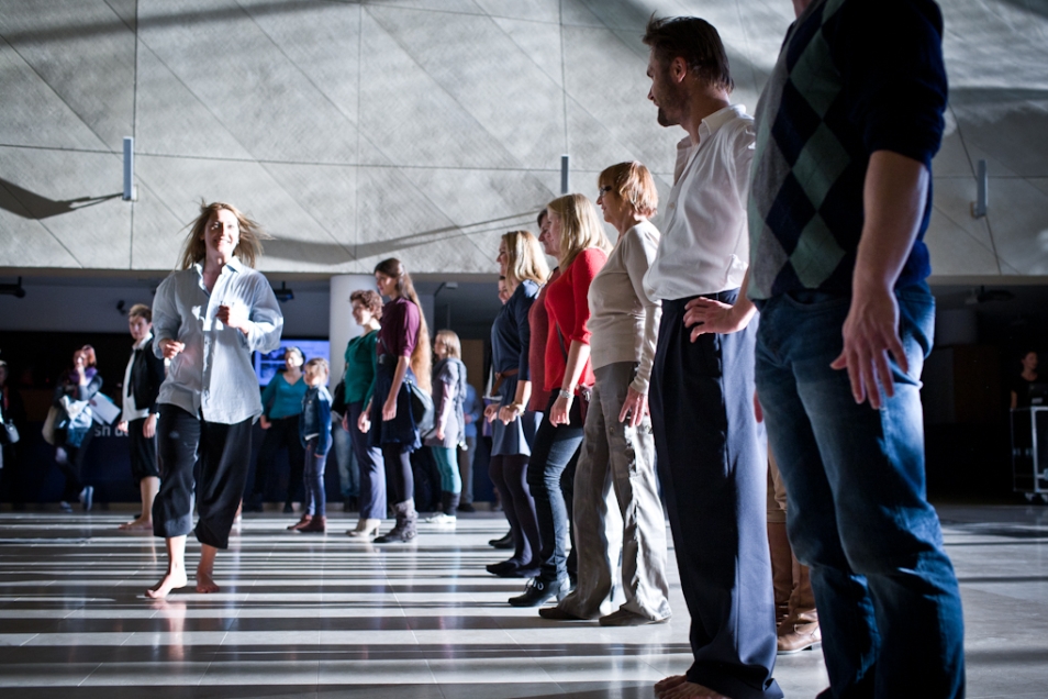 Grupa ludzi stoi w rzędzie podczas warsztatów tanecznych.
