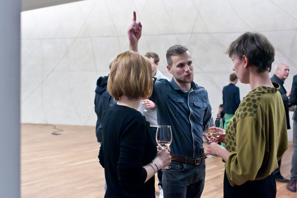 Trzy osoby rozmawiają ze sobą w holu głównym w Muzeum POLIN.