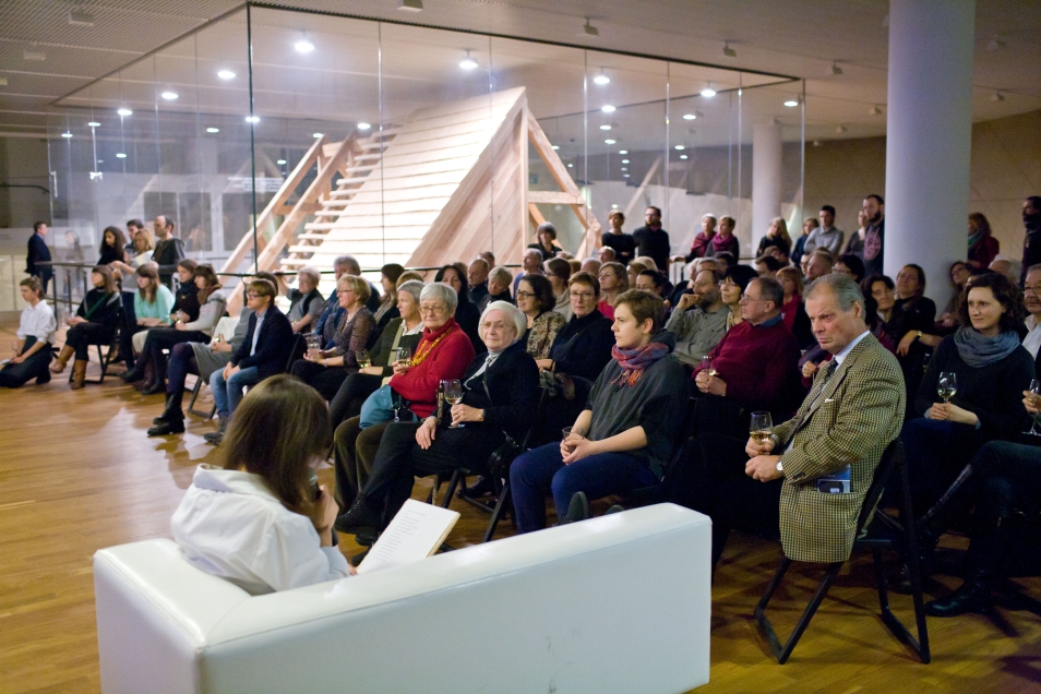 Grupa ludzi w pomieszczeniu ogląda spektakl teatralny.