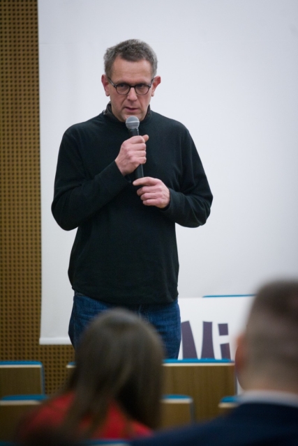 Mężczyzna mówi przez mikrofon podczas dyskusji "Uwierzyć w muzeum".