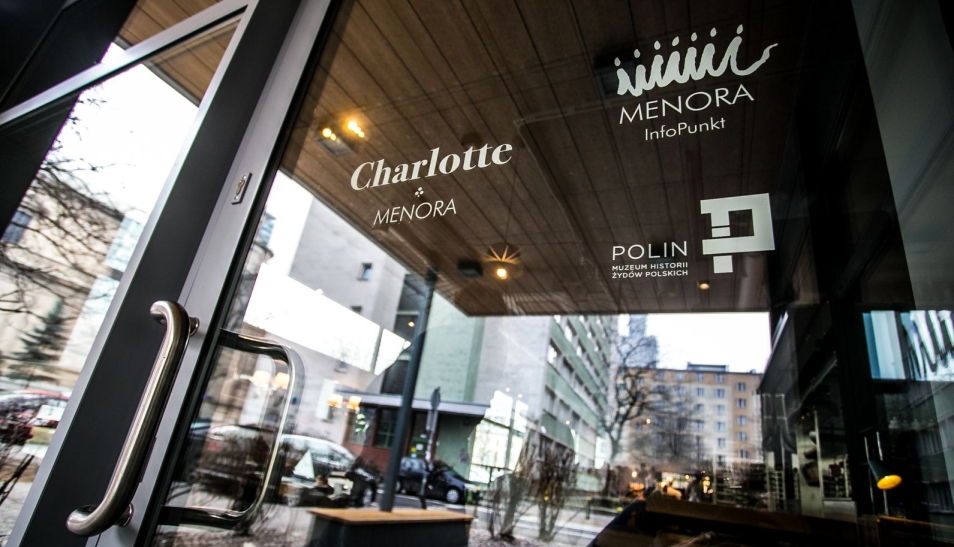 Szklana witryna z napisem Menora Infopunkt, logotypem POLIN i napisem Charlotte & Menora..