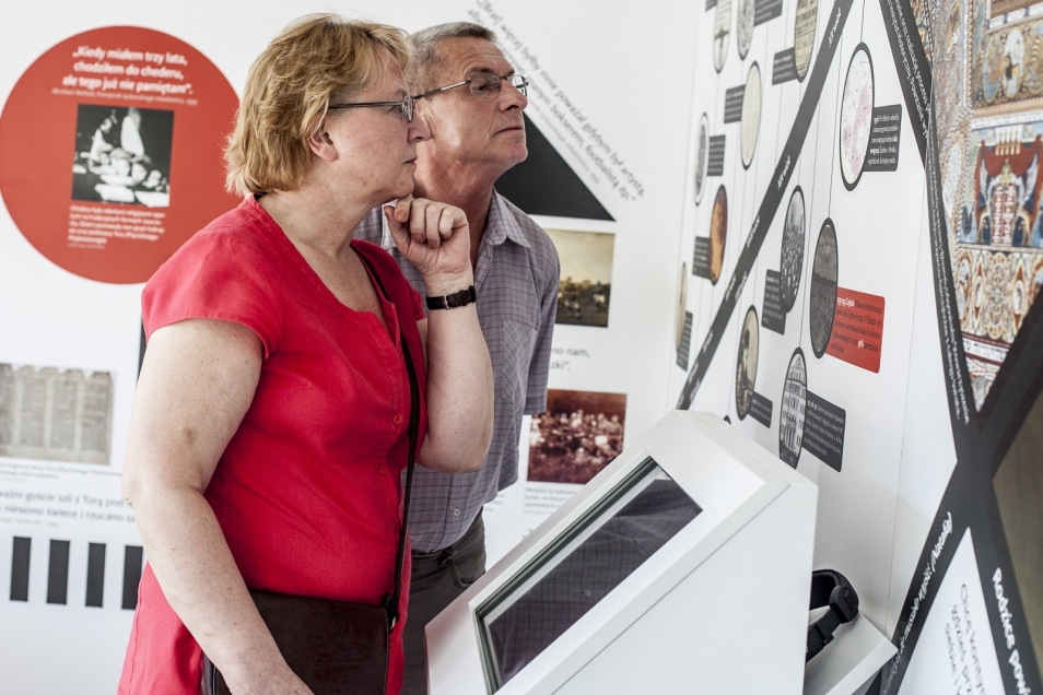 Muzeum na kółkach. Kobieta i mężczyzna wpatrują się w opisy na wystawie.