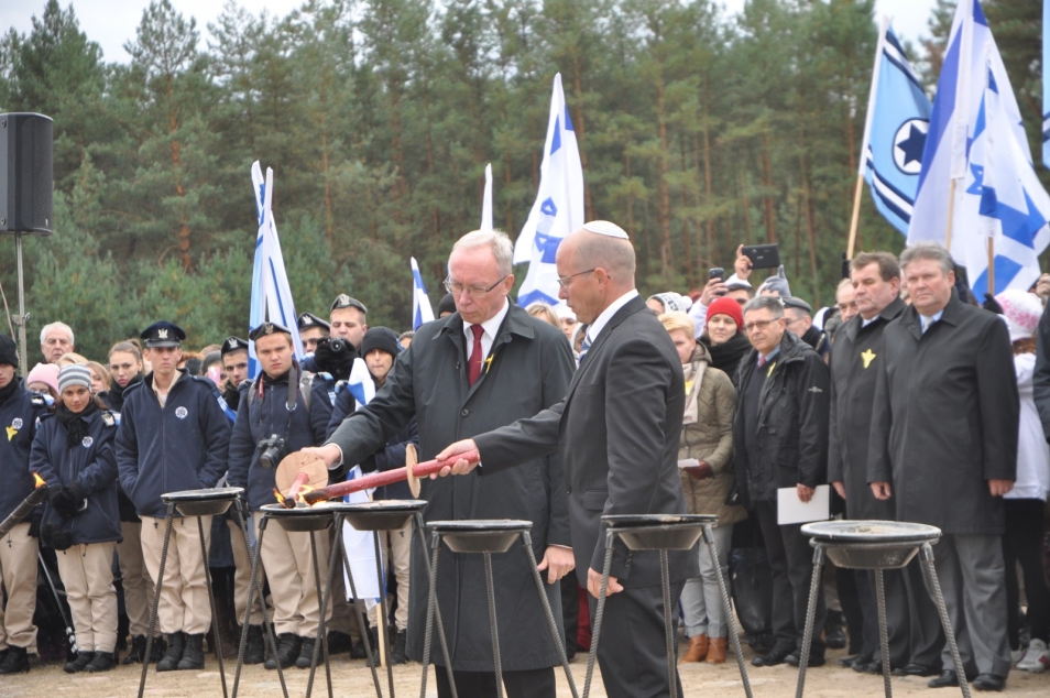 Dwaj mężczyźni zapalają pochodnie - w tle flagi izraelskie.