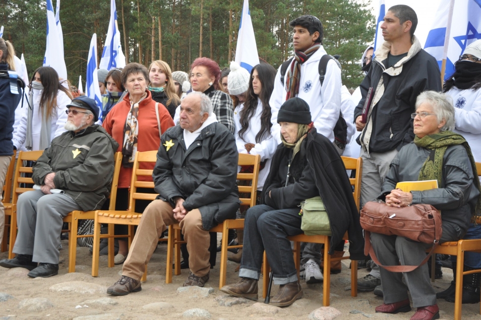 Kilka starszych osób siedzi na krzesłach podczas obchodów w Treblince w 2013 r.