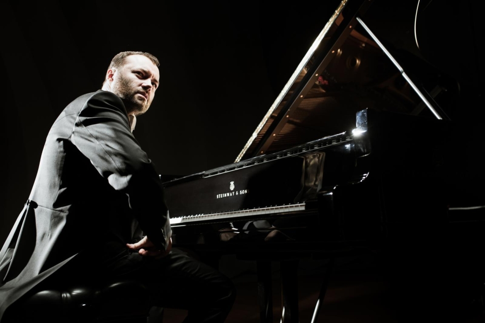 pianista Piotr Sałajczyk siedzi przy fortepianie
