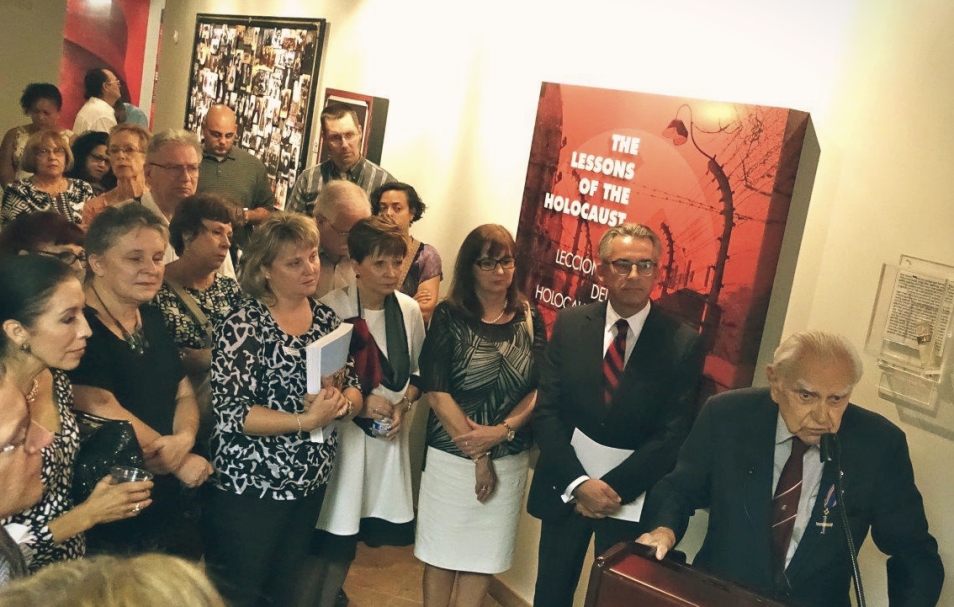 Grupa osób zgromadzona wokół przemawiającego profesora.