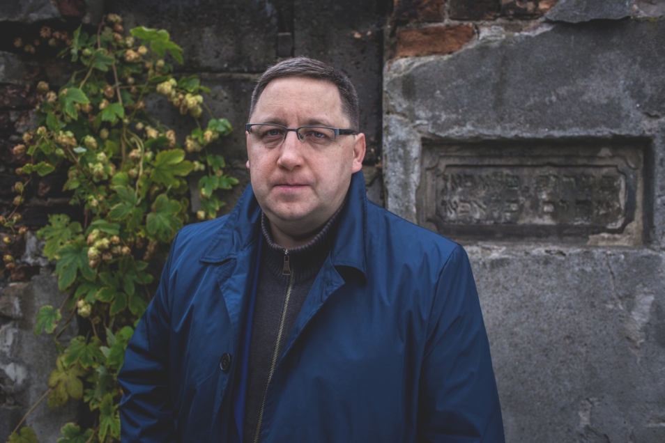 Robert Augustyniak na tle tablicy nagrobka żydowskiego.