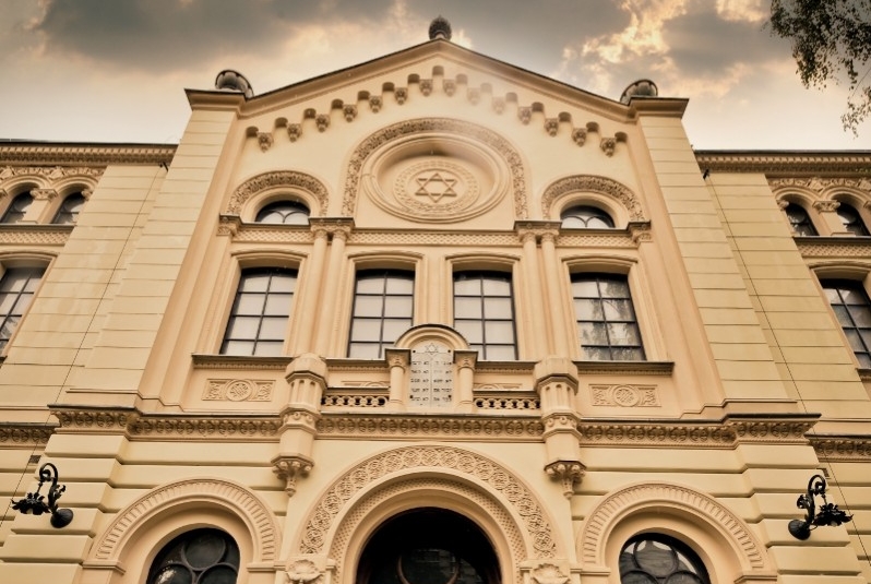 Frontowy widok z drzwiami i schodami Synagogi Nożyków na tle pochmurnego nieba