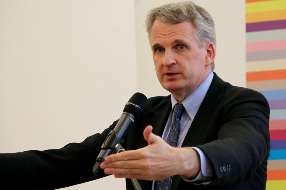 Prof. Timothy Snyder stoi przed mikrofonem, ma obie ręce wyciągnięte w stronę słuchaczy