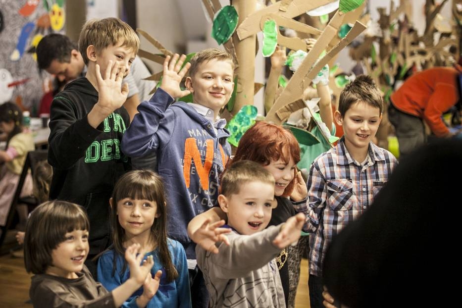 Grupa dzieci trzyma ręce w górze.