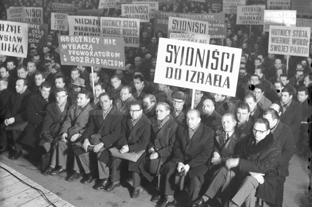 Wiec polityczny - grupa osób siedzi, wiele z nich trzyma transparenty z napisami Syjoniści do Izraela.