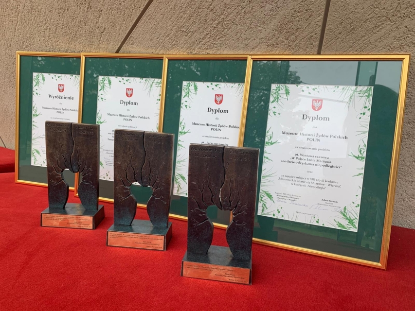 Nagrody "Wierzba 2018" dla wystaw muzeum POLIN - na zdjęciu dyplomy oprawione w złote cienkie ramki oraz statuetki - wykonane z brązu, z przedstawieniem wierzby iwy, symbolu nagrody.