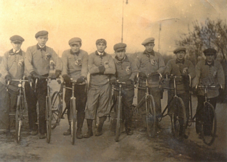 Zdjęcie archiwalne przedstawia grupę mężczyzn stojących przy rowerach.