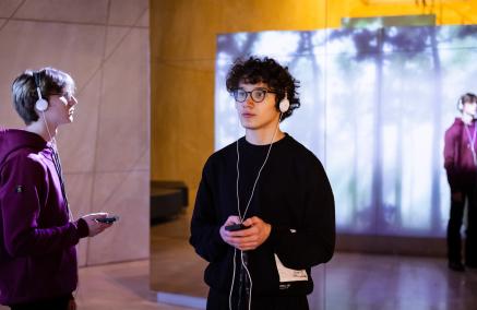 Dwóch nastolatków zwiedza wystawę stałą Muzeum POLIN, korzystając z audiogry.
