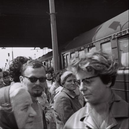 Archiwalne zdjęcie przedstawia ludzi stojących na stacji kolejowej.