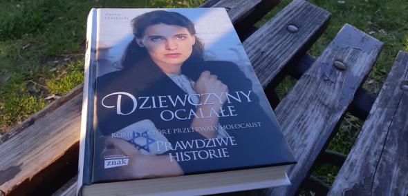 Okładka książki Anna Herbich "Dziewczyny ocalałe" - książka leży na ławce w parku.
