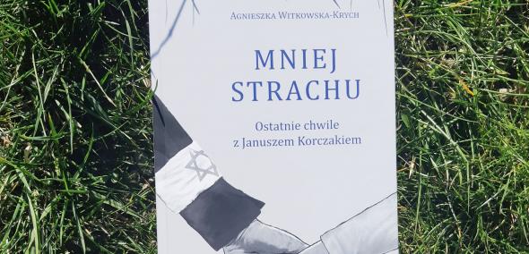 Okładka książki: Agnieszka Witkowska-Krych "Mniej strachu. Ostatnie chwile z Januszem Korczakiem". Książka leży na trawie