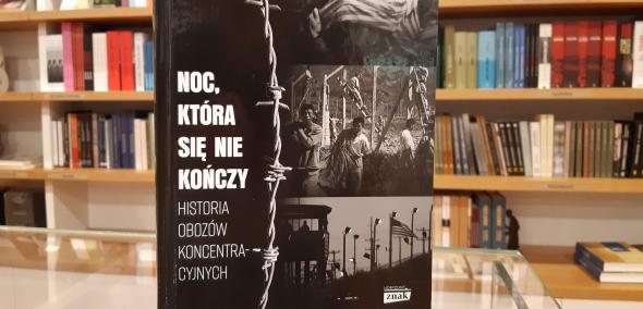Okładka książki Andrea Pitzer "Noc, która się nie kończy. Historia obozów koncentracyjnych". W tle regał księgarniany, z wieloma innymi książkami