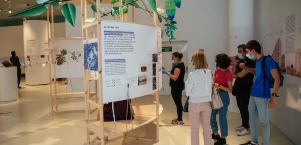 Grupa ludzi na wystawie Tu Muranów, przy fragmencie opowiadającym historię Ogrodu Krasińskich