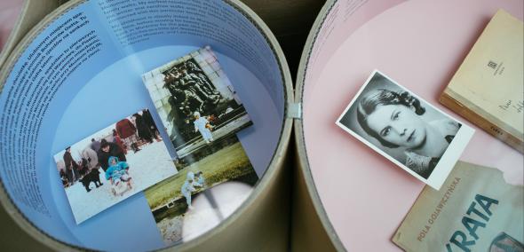 W Tubach z kartony, których wnętrze jest w kolorach pastelowych - niebieskim i różowym - znajdują się pamiątki mieszkańców Muranowa: fotografie, ulotki, książki