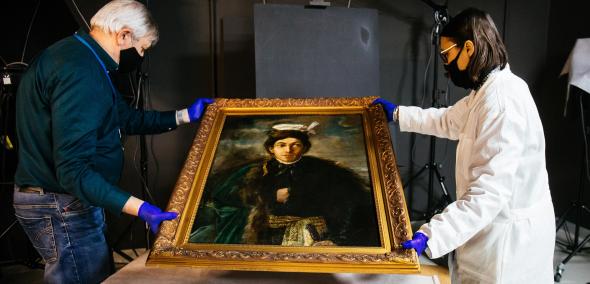 Na obrazie widzimy dwie osoby - kobietę i mężczyznę trzymających obraz Maurycy Gottlieb - „Autoportret w stroju polskiego szlachcica”