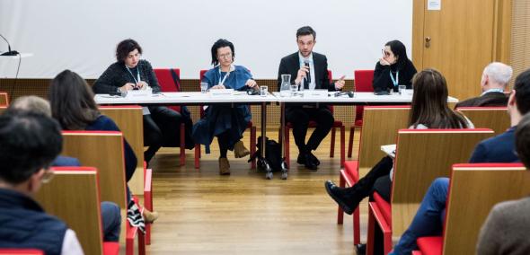Sala wykładowa, za stołem plenarnym czworo panelistów. Na krzesłach siedzą słuchacze wykładu