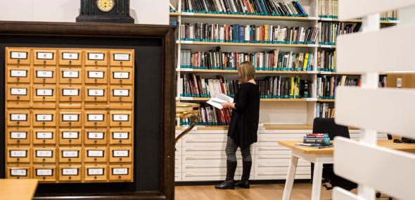 Centrum Informacji Historycznej w Muzeum POLIN. Przy regale z książkami stoi kobieta i przegląda jakąś książkę.