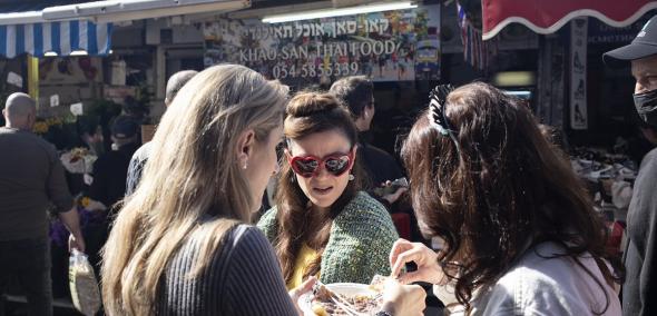 Trzy kobiety dzielą się jedzeniem podczas festiwalu kulinarnego.