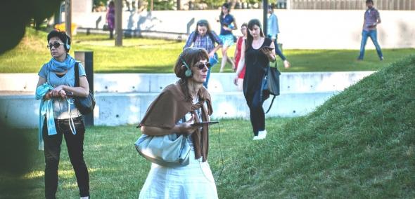 Kilka kobiet w słuchawkach spaceruje po zielonej łące przy Muzeum POLIN.