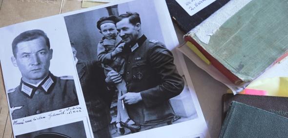 Kadr z filmu "Dobry i zły nazista". Na stole leżą rozrzucone fotografie z podobizną Wilma Rosenfelda - bohatera dokumentu.