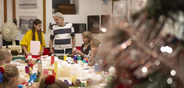 Uczestnicy wydarzenia Gwiazdka na Muranowie siedzą przy stole i tworzą ozdoby świąteczne.