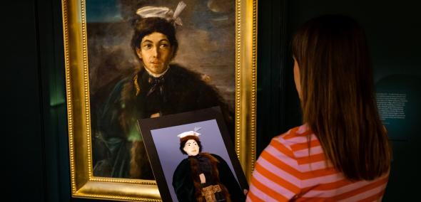 Kobieta stoi przy obrazie Maurycego Gottlieba na wystawie stałej w Muzeum POLIN i trzyma przed sobą tyflografikę tego obrazu.