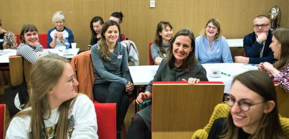Grupa uśmiechniętych osób, głównie kobiet, siedzi na krzesłach w sali konferencyjnej w Muzeum POLIN.